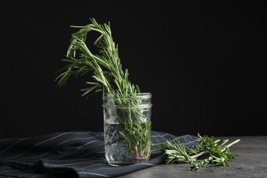 Fresh green rosemary in jar on table, space for text