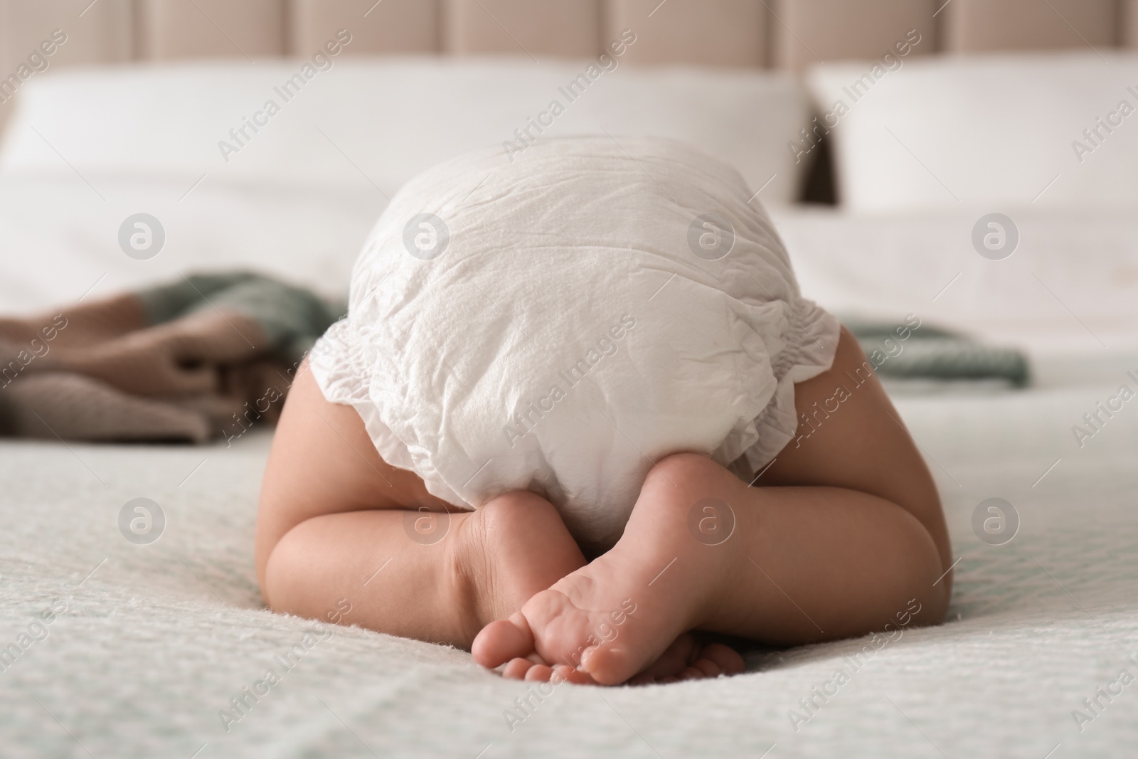 Photo of Cute little baby in diaper on bed at home