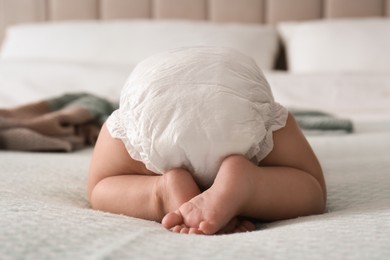 Cute little baby in diaper on bed at home