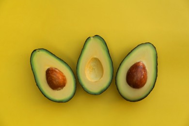 Photo of Fresh avocado halves on yellow background, flat lay