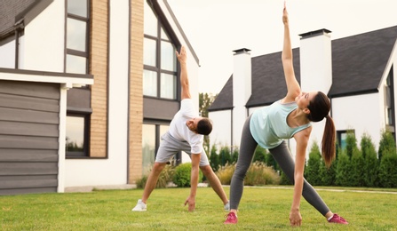 Photo of Sporty couple practicing morning yoga at backyard. Healthy lifestyle