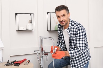 Photo of Man installing new water tap in bathroom