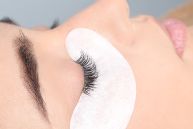 Young woman undergoing eyelashes extensions procedure, closeup