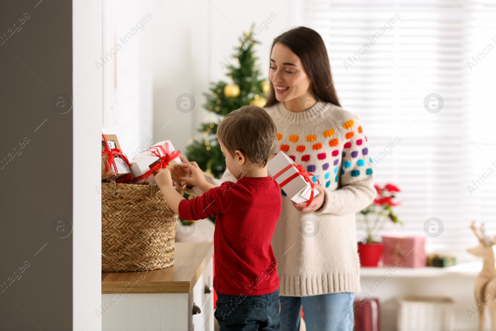 Photo of Mother and son with Christmas gifts at home. Advent calendar in basket