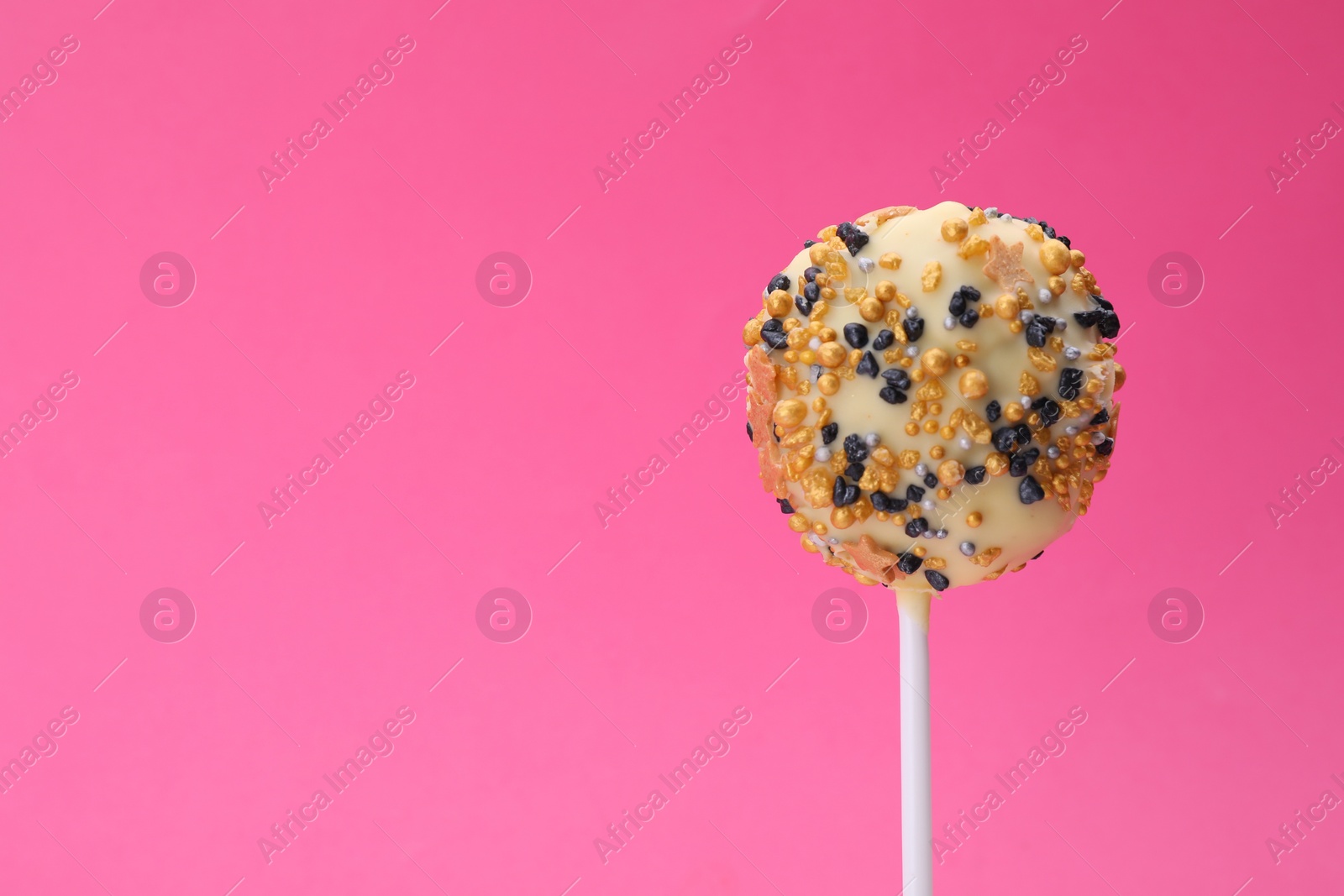 Photo of Delicious confectionery. Sweet cake pop decorated with sprinkles on pink background, closeup. Space for text