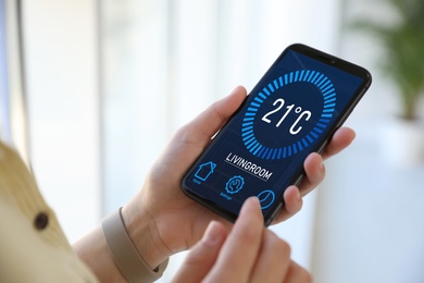 Image of Man using smartphone to control heating system in house, closeup