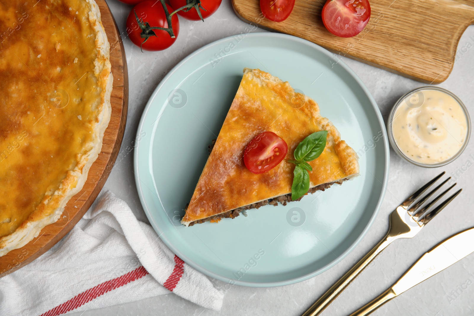 Photo of Piece of delicious pie with minced meat, tomato and sauce served on light marble table, flat lay