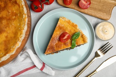 Piece of delicious pie with minced meat, tomato and sauce served on light marble table, flat lay