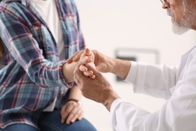 Photo of Orthopedist examining patient with injured hand in clinic, closeup