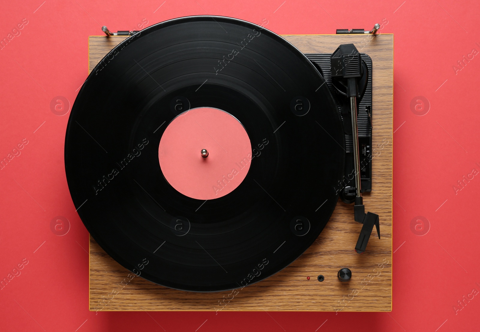 Photo of Modern turntable with vinyl record on red background, top view