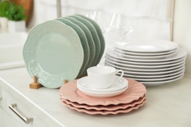 Photo of Clean plates and cup on white marble countertop in kitchen