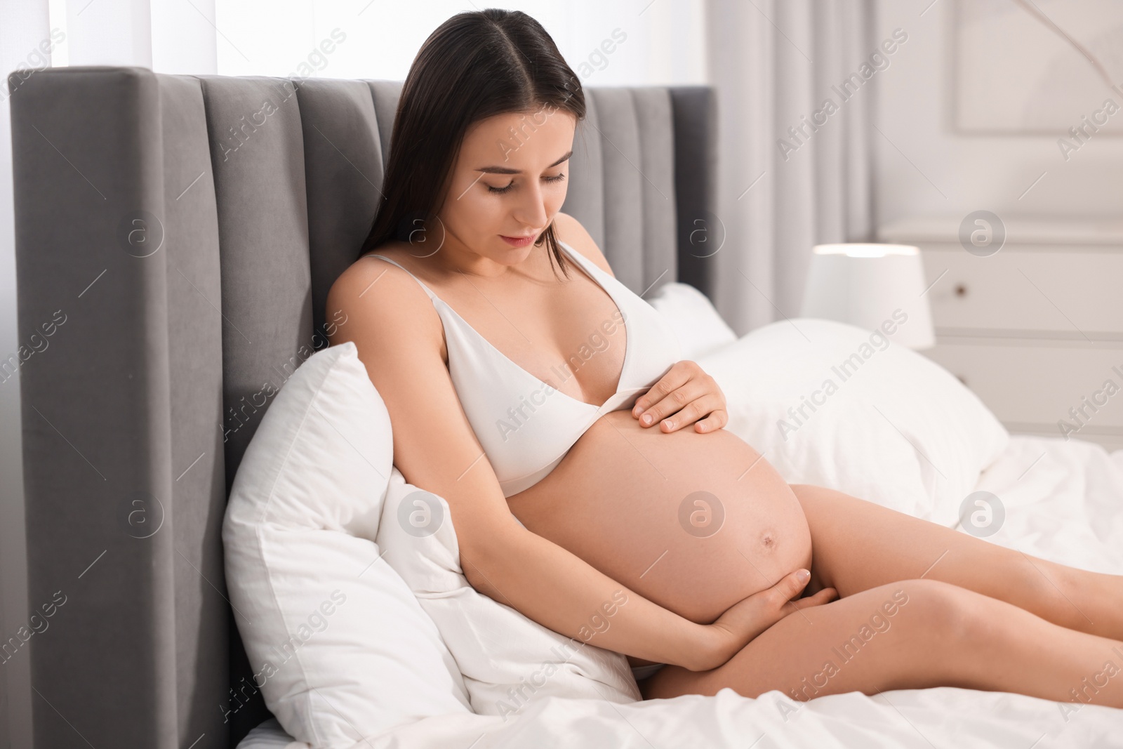 Photo of Beautiful pregnant woman in stylish comfortable underwear on bed at home