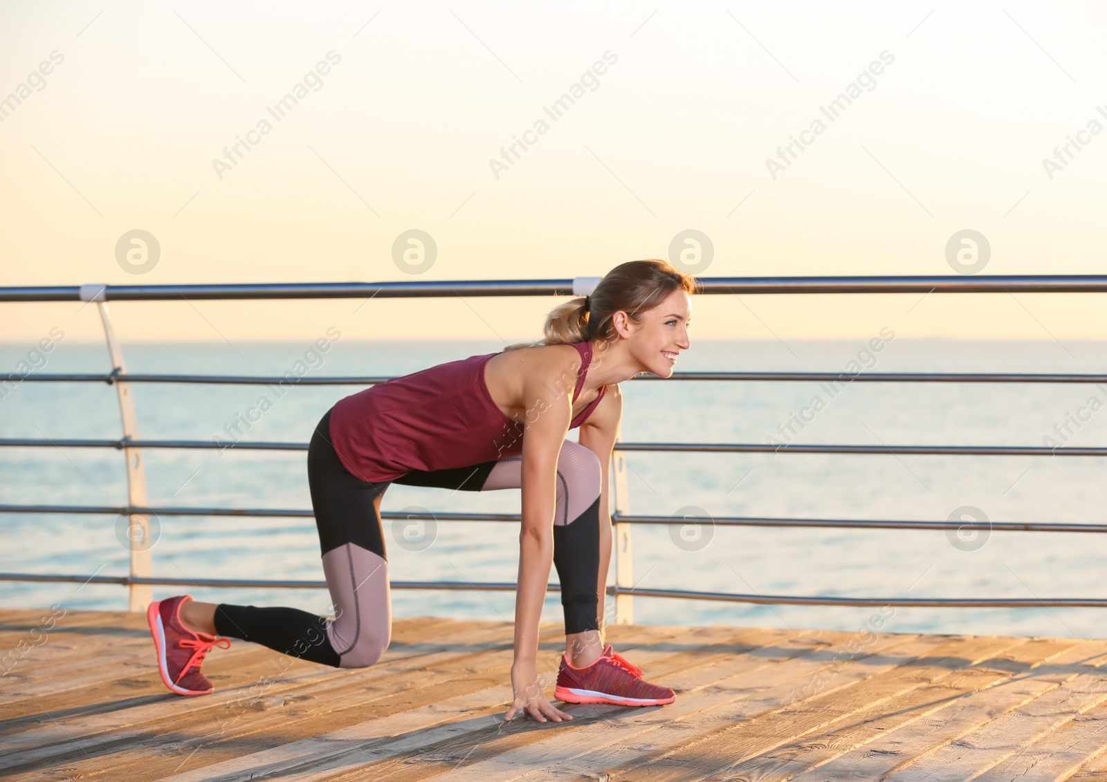 Photo of Fitness woman in position ready to run on pier in morning