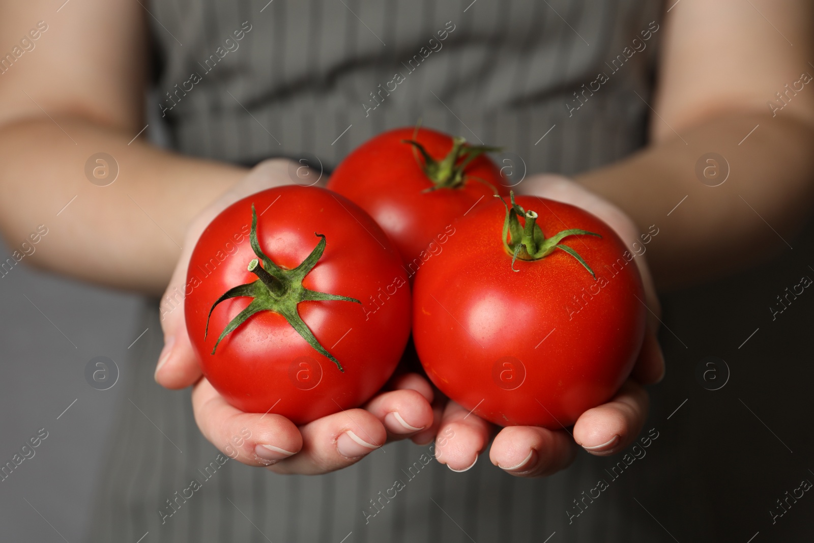 Photo of Woman with ripe tomatoes on grey background, closeup