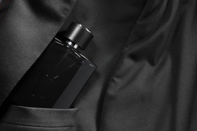 Photo of Luxury men's perfume in breast pocket of black jacket, top view. Space for text