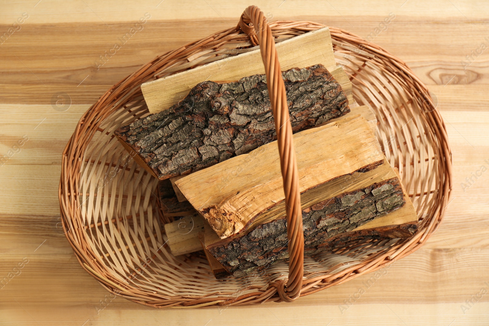 Photo of Wicker basket with firewood on floor indoors, top view