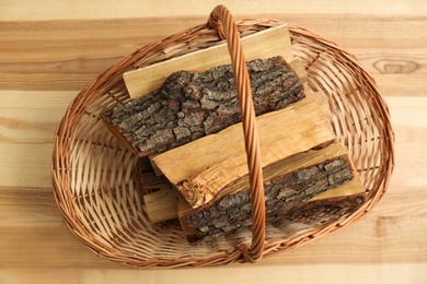 Wicker basket with firewood on floor indoors, top view