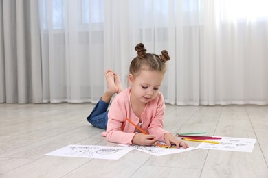 Photo of Cute little girl coloring on warm floor at home. Heating system