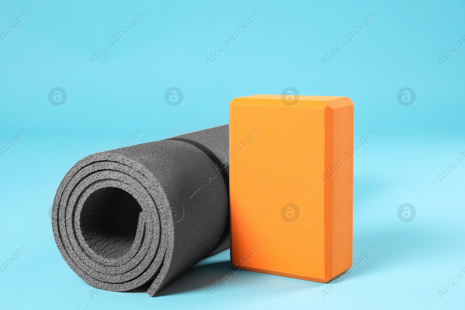 Photo of Exercise mat and yoga block on light blue background