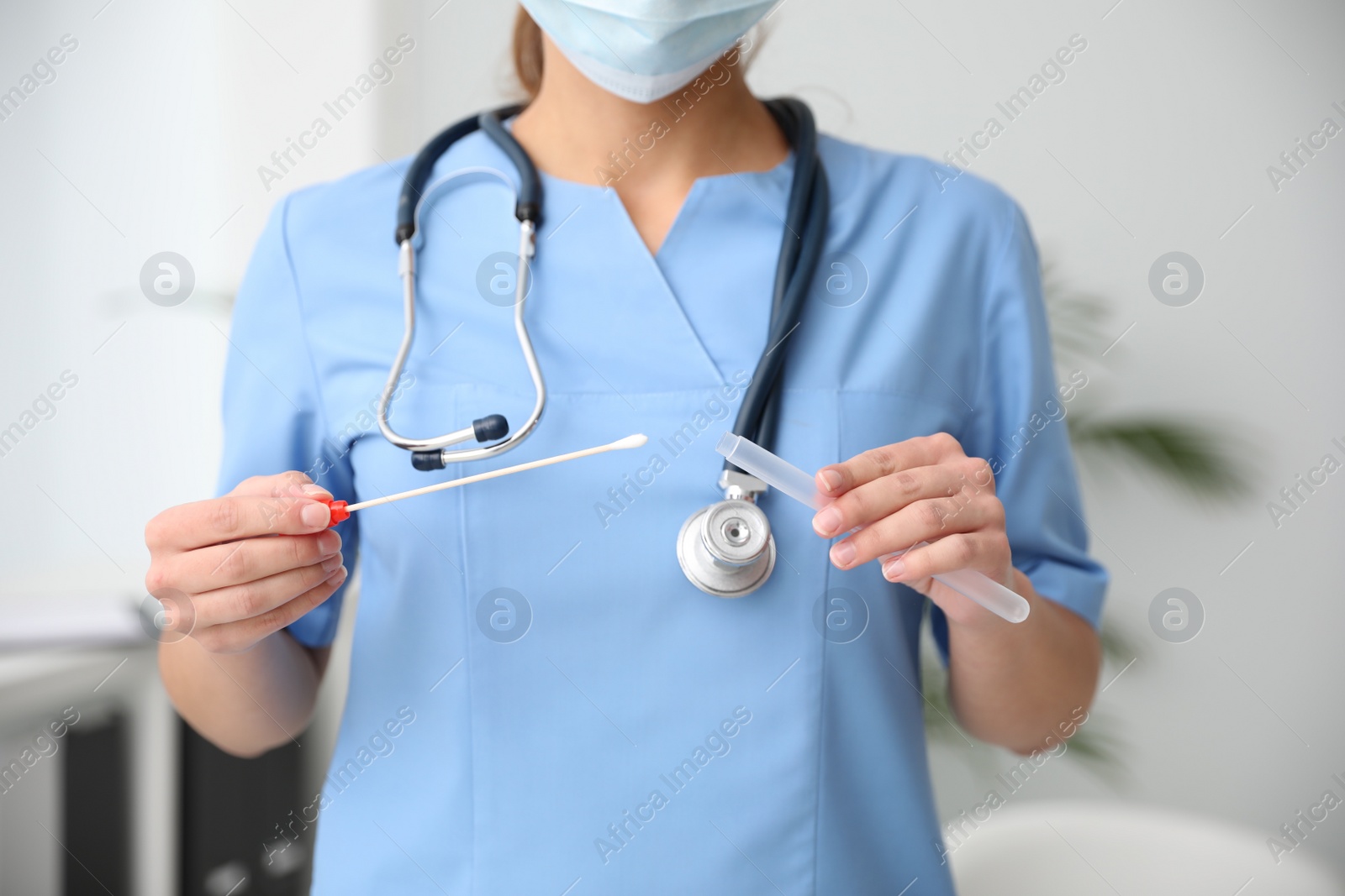 Photo of Doctor holding buccal cotton swab and tube for DNA test in clinic, closeup