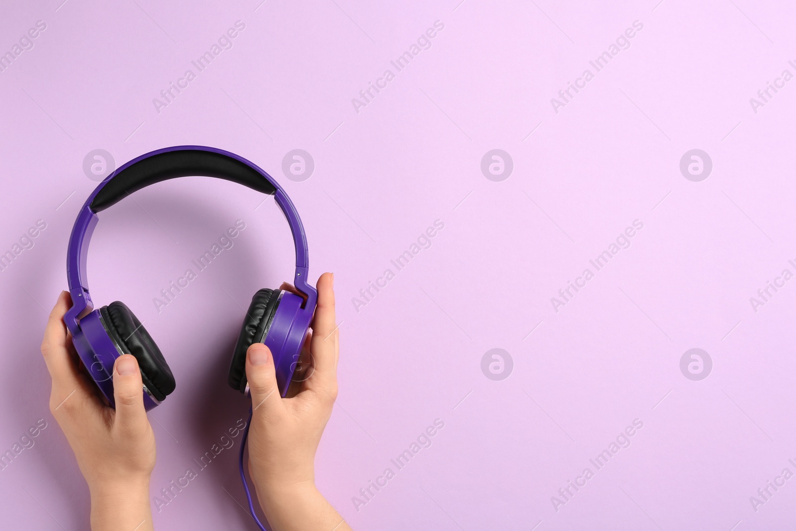 Photo of Woman holding stylish headphones on color background, closeup. Space for text