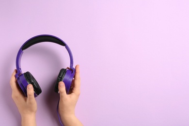 Woman holding stylish headphones on color background, closeup. Space for text