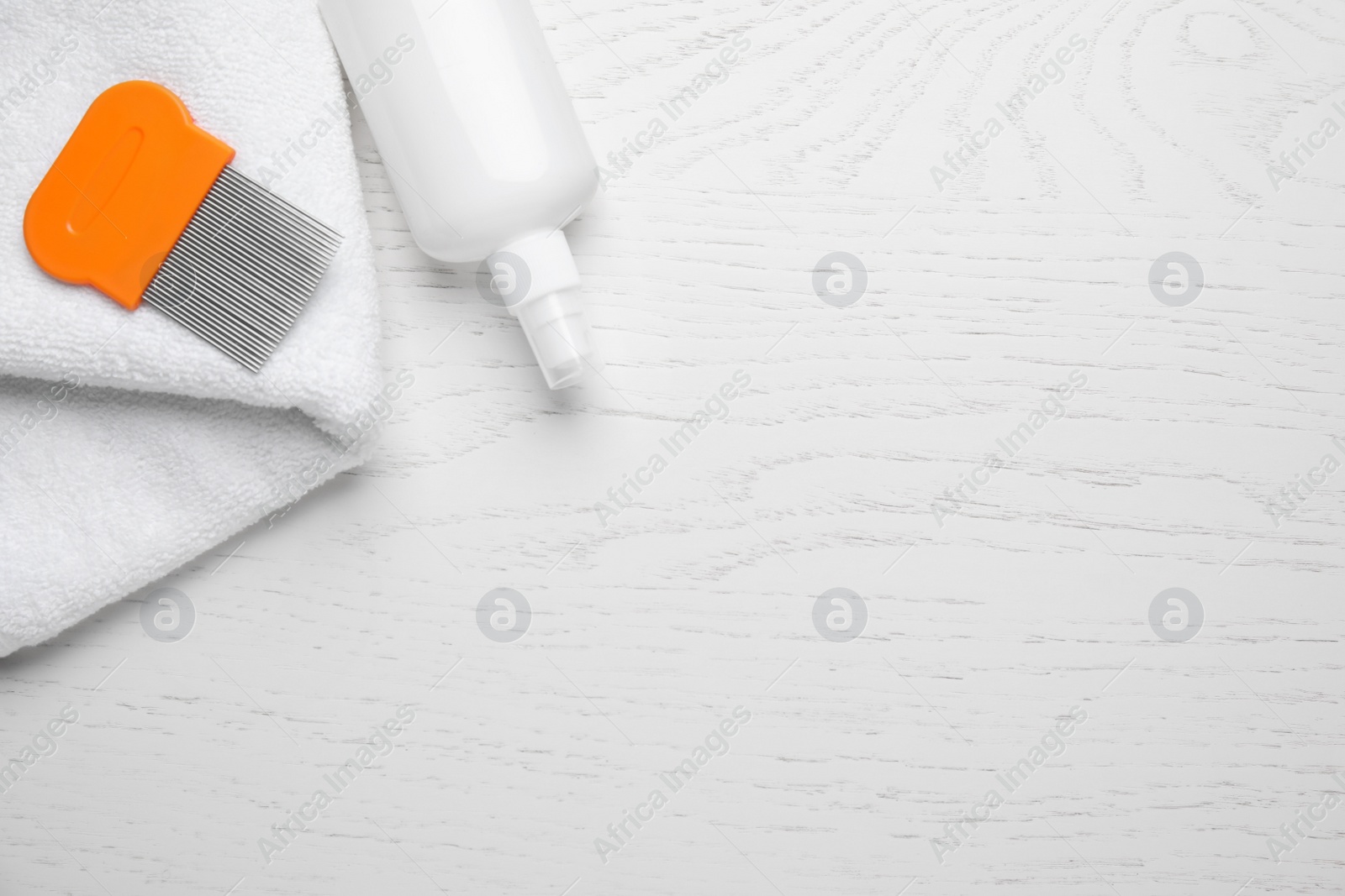 Photo of Spray, metal comb and towel for anti lice treatment on white wooden background, flat lay. Space for text