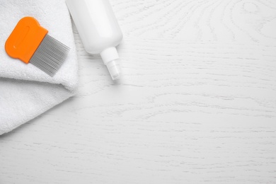 Photo of Spray, metal comb and towel for anti lice treatment on white wooden background, flat lay. Space for text
