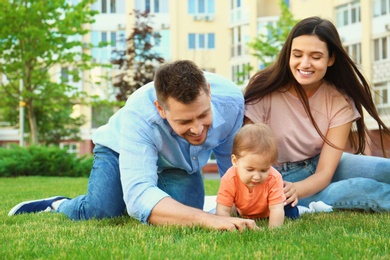 Parents helping their adorable little baby to crawl outdoors