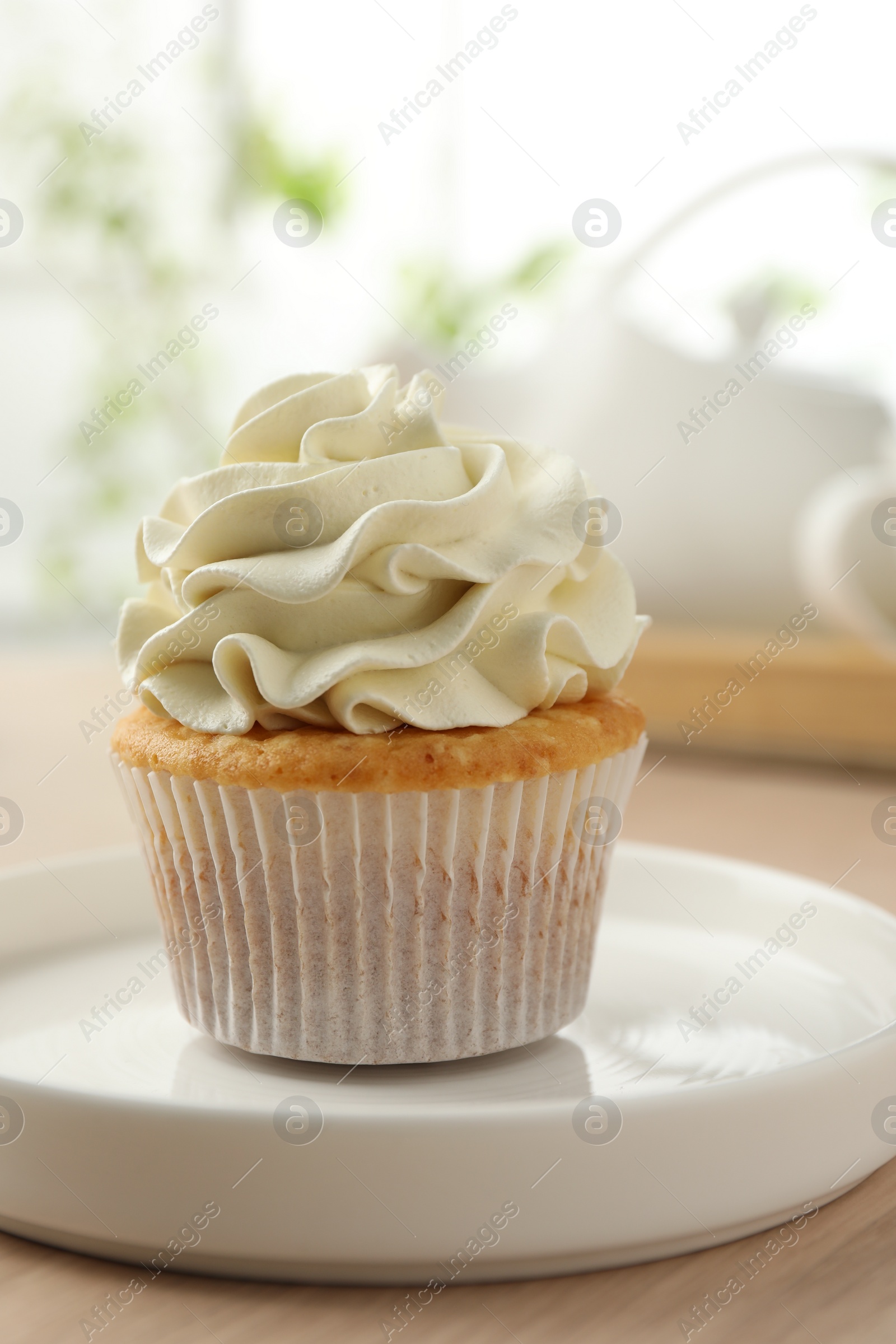 Photo of Tasty cupcake with vanilla cream on light wooden table, closeup