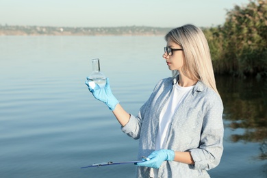 Scientist with clipboard and sample taken from river