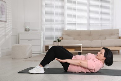 Photo of Overweight mature woman doing abs exercise at home, space for text
