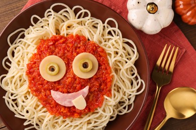 Photo of Plate with funny monster made of tasty pasta served on wooden table, flat lay. Halloween food
