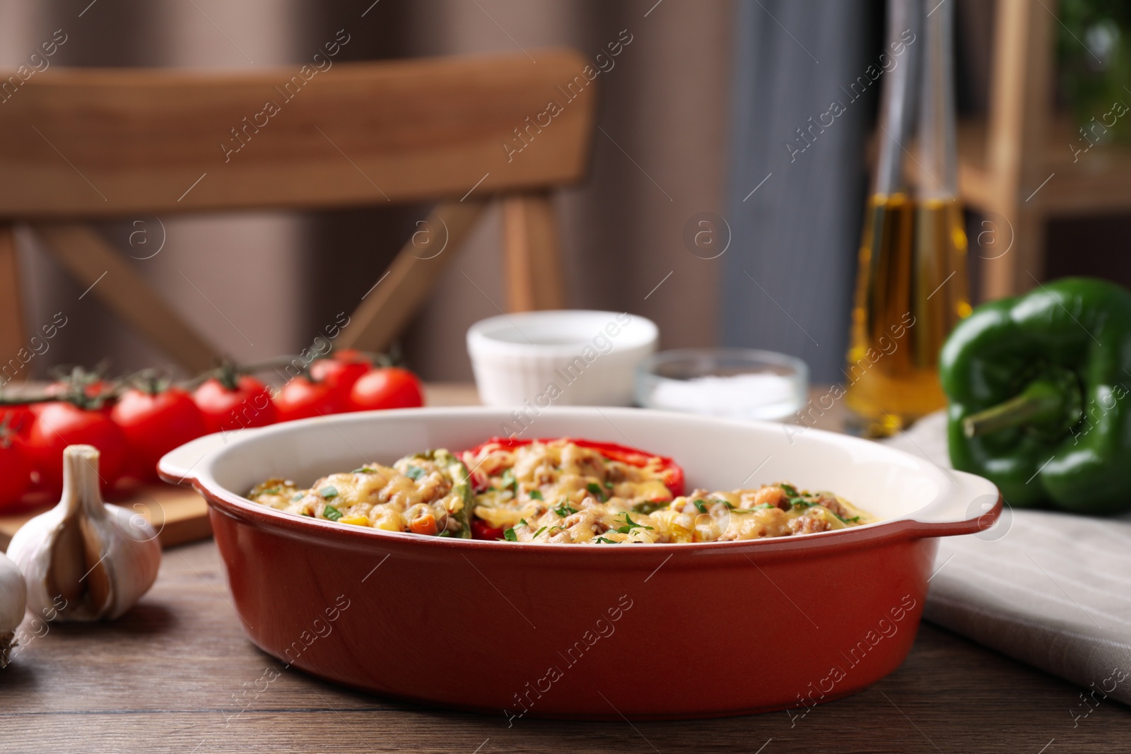 Photo of Tasty stuffed bell peppers in baking dish on wooden table in kitchen