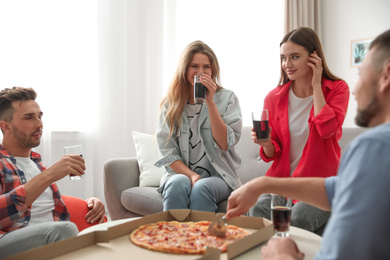 Photo of Group of friends with drinks and pizza at home