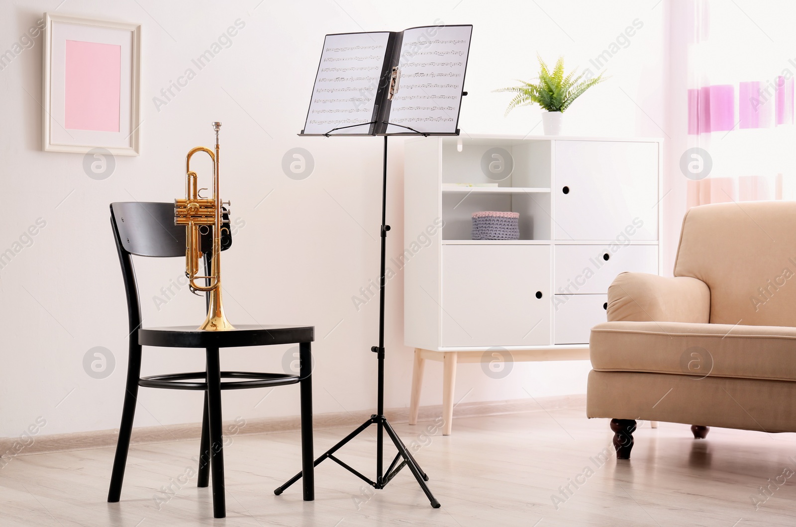 Photo of Trumpet, chair and note stand with music sheets in room