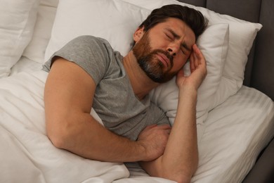 Photo of Man suffering from headache in bed at night