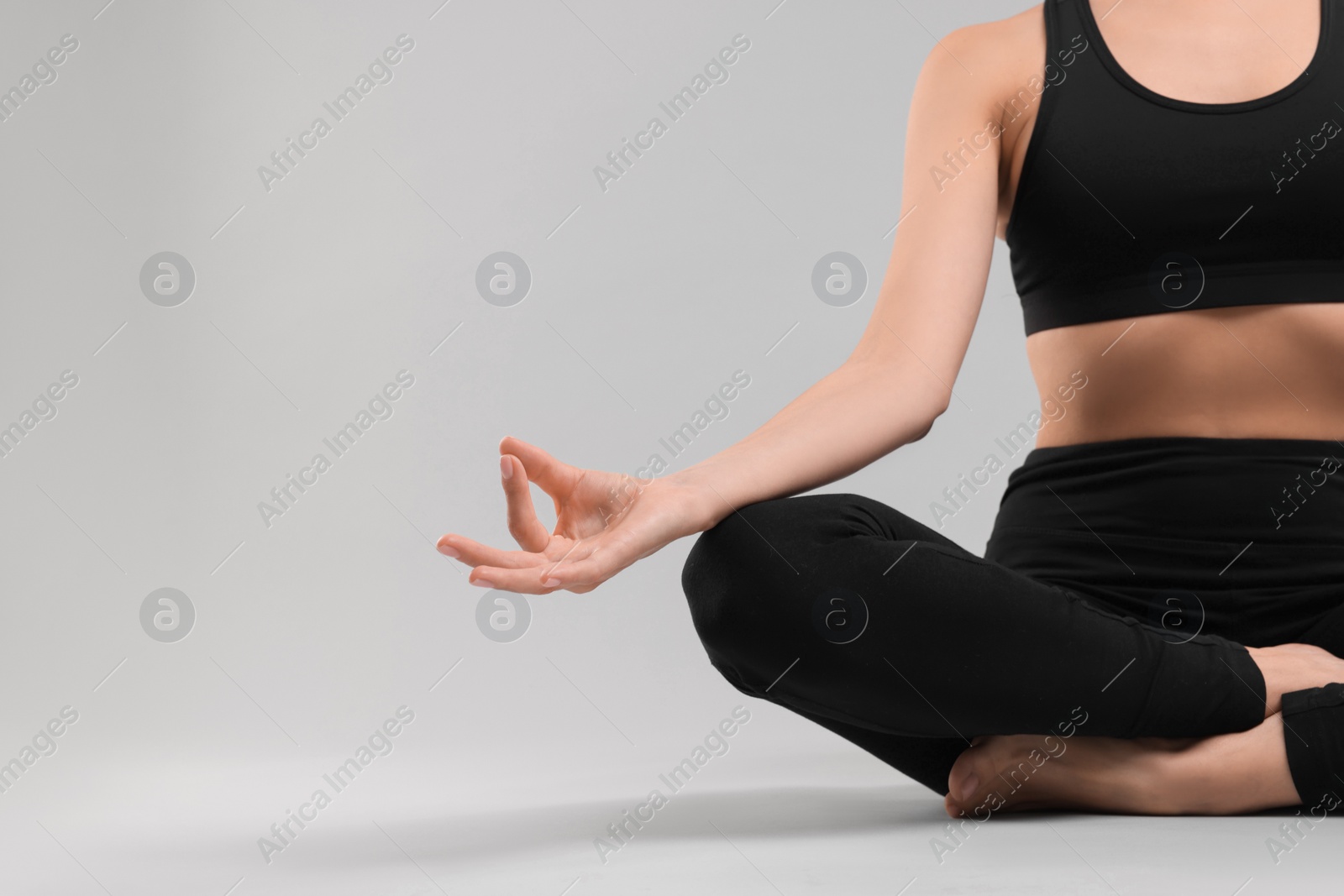 Photo of Woman practicing yoga on grey background, closeup and space for text. Lotus pose