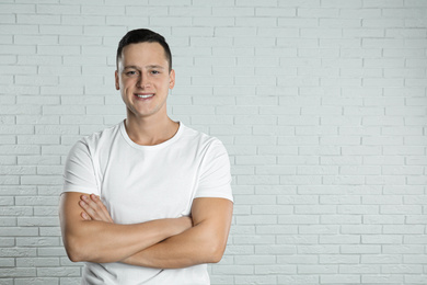 Handsome young man near white brick wall