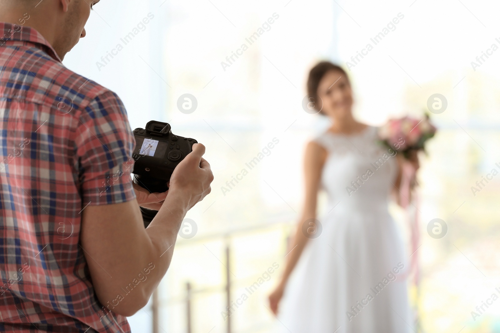 Photo of Professional photographer with camera and beautiful bride in studio