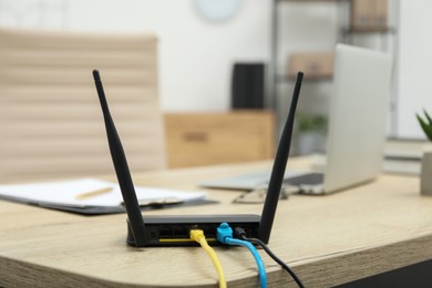 Modern Wi-Fi router on wooden table indoors