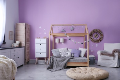 Photo of Child's room interior with comfortable bed and garland