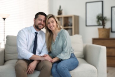 Photo of Blurred view of happy couple sitting on sofa at home