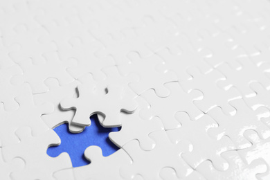 Photo of Blank white puzzle with separated piece on blue background. Space for text