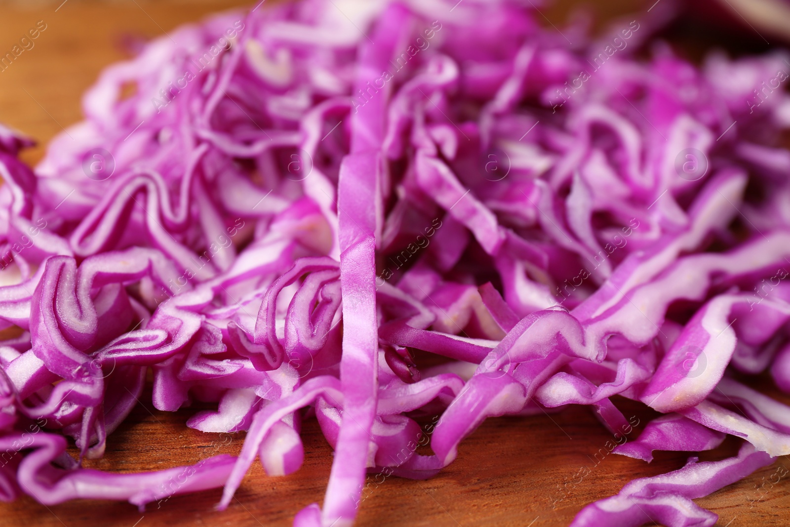 Photo of Heap of shredded fresh red cabbage on wooden table, closeup