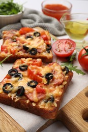 Tasty pizza toasts and ingredients on white table, closeup