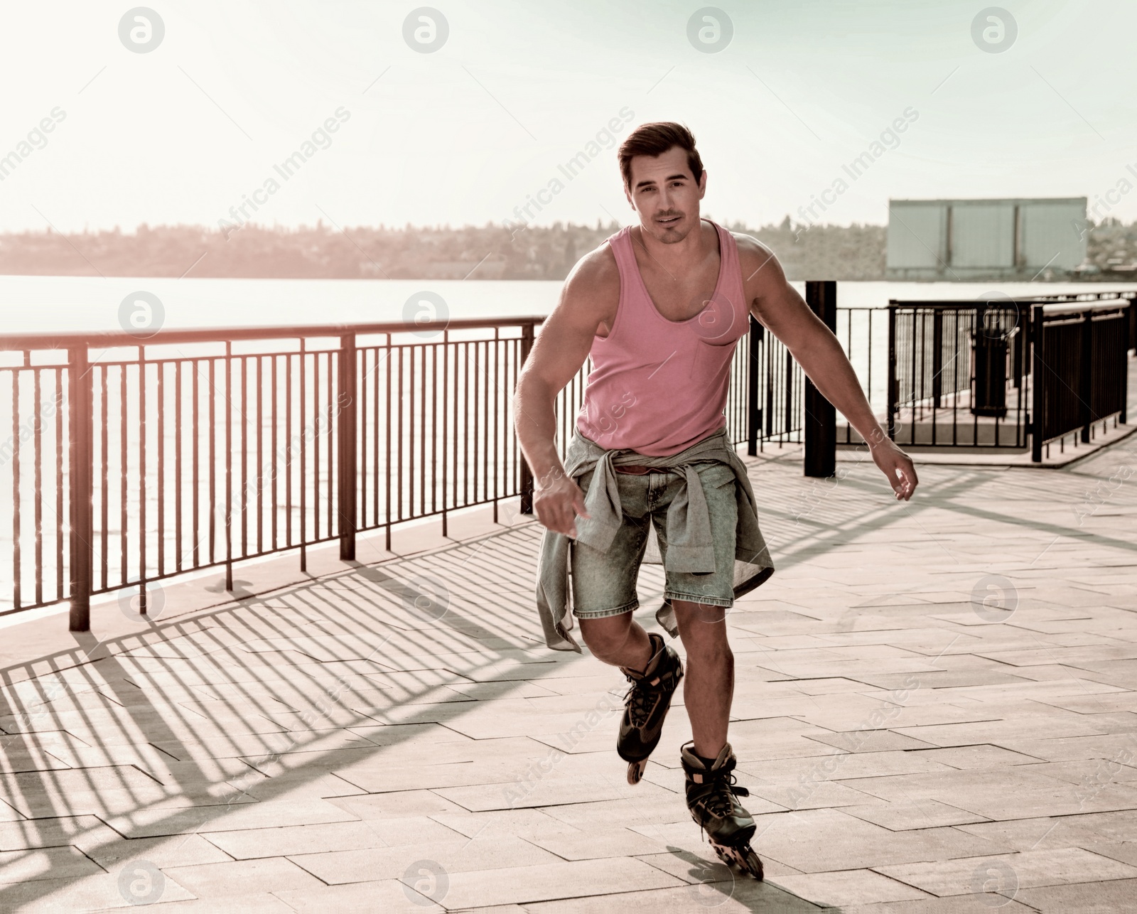 Image of Handsome young man roller skating on pier near river, space for text