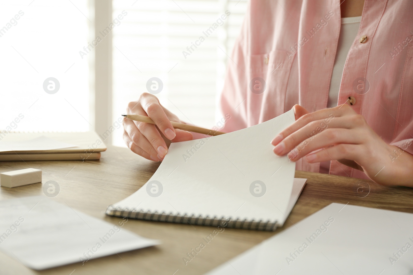Photo of Woman with pencil and notepad at wooden table, closeup