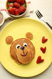 Creative serving for kids. Plate with strawberries, cute bear made of pancakes on light wooden table, flat lay