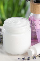 Different hand care cosmetic products and lavender flowers on white wooden table, closeup